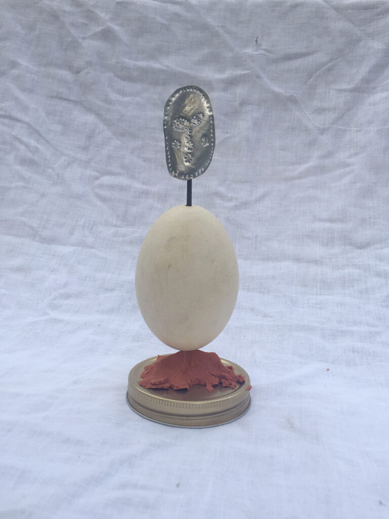 A small sculpture made up of: Can, File, Casting Sand, Egg, Lid