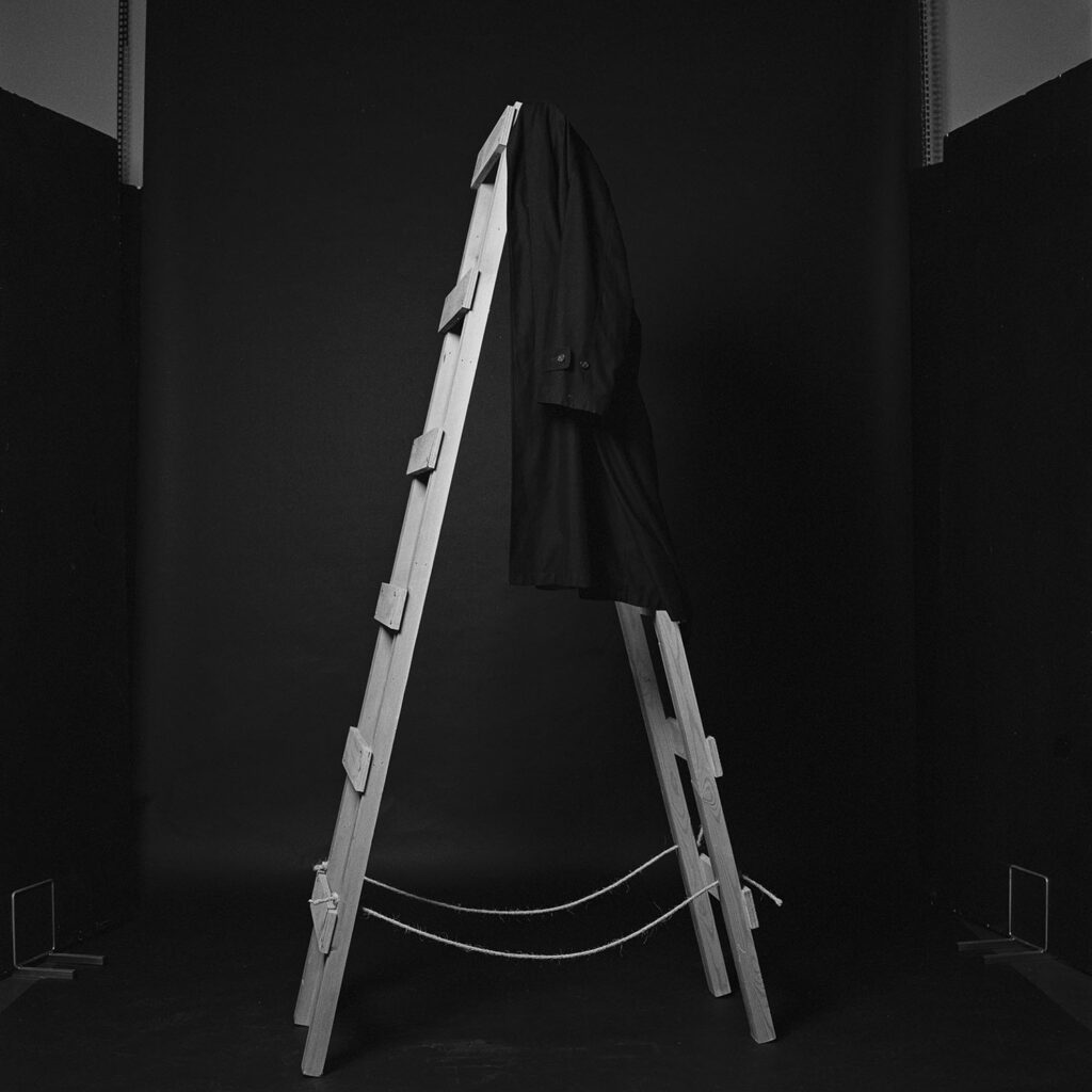 Black and white photograph of step-ladder and coat