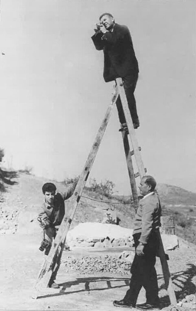 Old photograph of photographer on step-ladder with two other men